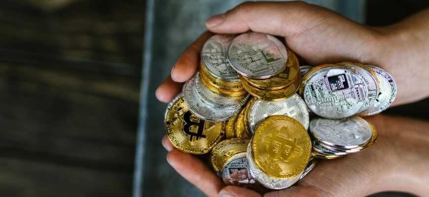 A close-up of hands holding various cryptocurrency coins, representing digital finance.